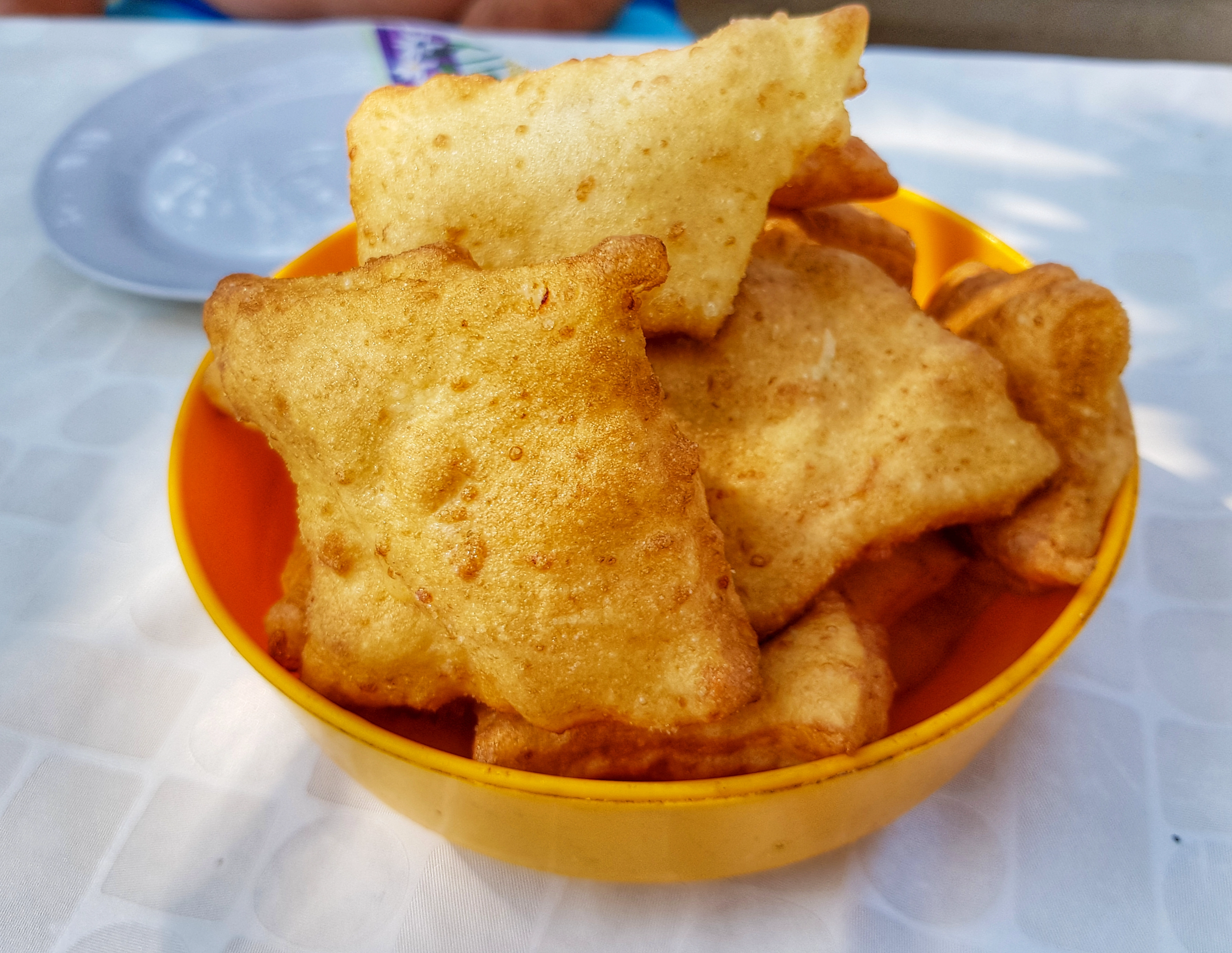 gnocchi fritti in un piatto arancione su un tavolo con atmosfera estiva